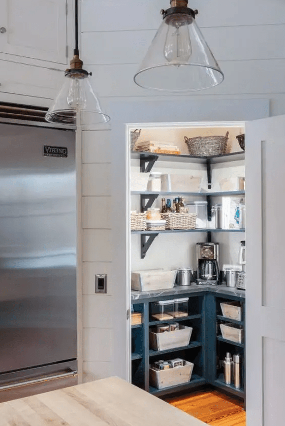 A small and stylish pantry with open shelves and built-in cupboards, baskets and jars, as well as a few lights is a cool idea