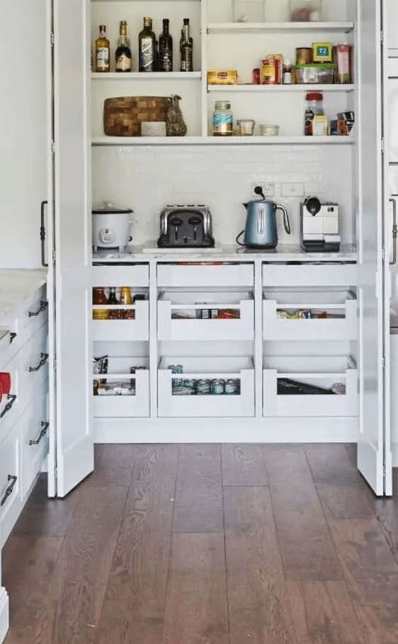 A small built-in pantry with open shelves, drawers, some appliances and groceries keeps the kitchen clean and tidy