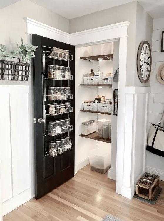 a small farmhouse pantry with shelves, lights, compartments, a door with a metal shelf and spices on it