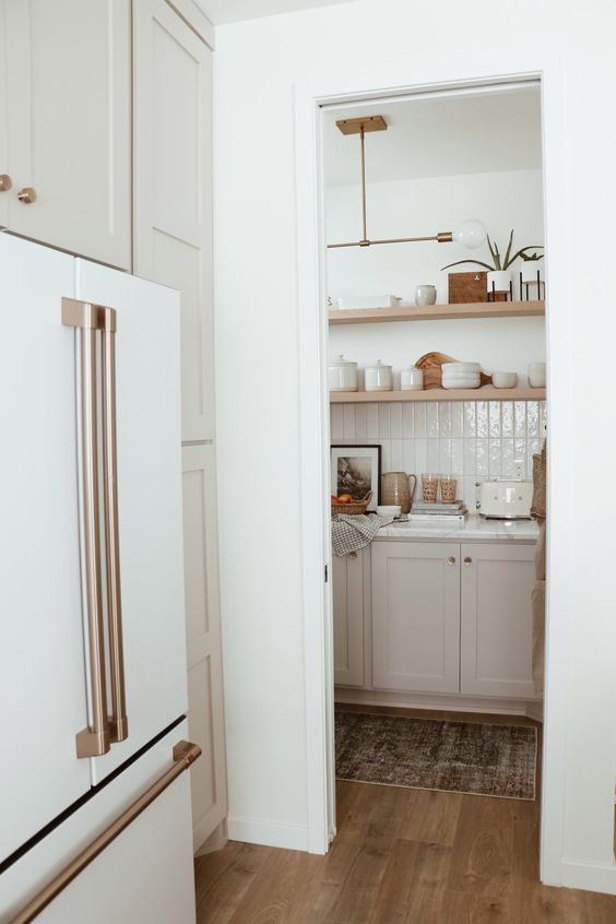 a small walk-in pantry with cabinets, open shelves, a tiled backsplash and even various decorations