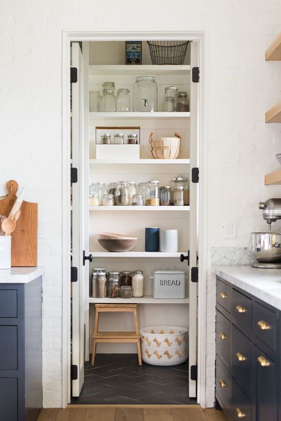 a small, well-organized pantry with open shelves, a ladder and lots of jars, as well as doors to hide them and make the kitchen tidier