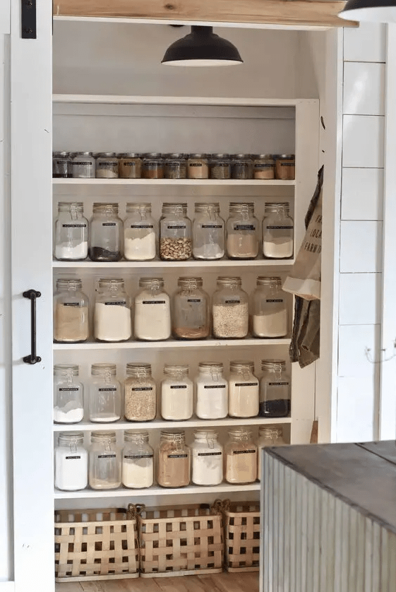 a cleverly organized pantry with open shelves, compartments, lots of jars to store all the food you want and a sliding door