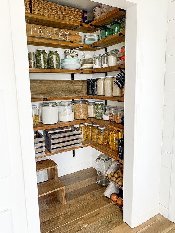 A farmhouse walk-in pantry with stained shelves, a ladder, some baskets, and lots of soft glassware is a beautiful space