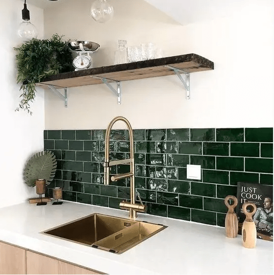 A neutral, modern kitchen with white countertops and hunter green subway tiles and gold fixtures for a more elegant look