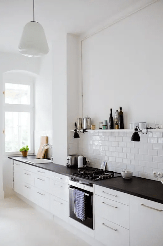 a serene Scandinavian kitchen with just base cabinets and dark butcher block countertops, a white subway tile backsplash, and shelving