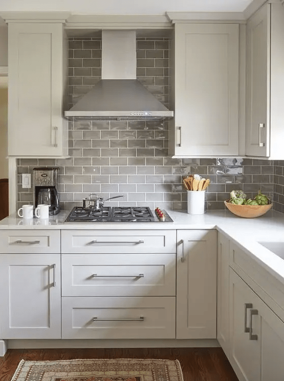 A white farmhouse kitchen with light gray subway tile and stainless steel backsplash completes the look