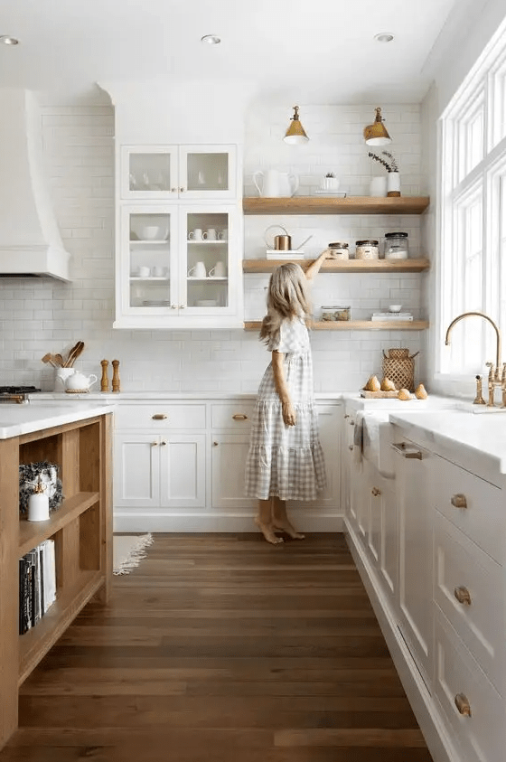 a white farmhouse kitchen with white stone countertops, a white subway tile backsplash, open shelving and a stained kitchen island