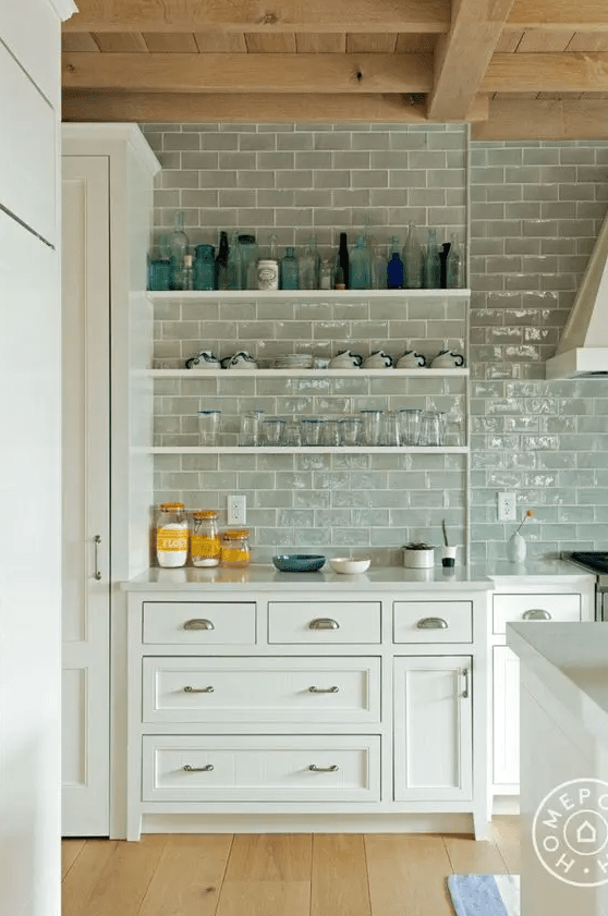 a white modern farmhouse kitchen with shaker cabinets, open shelving and gray subway tile along the entire wall