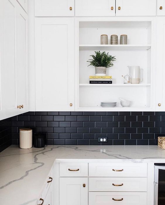 A white modern farmhouse kitchen with white countertops and a black matte subway tile backsplash for contrast