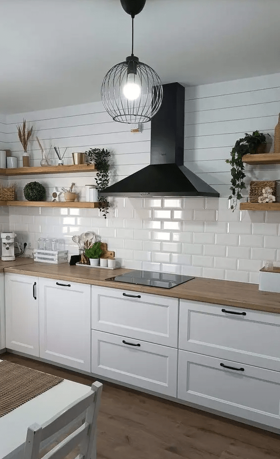 a white Nordic kitchen with shaker cabinets, a white subway tile backsplash, open shelving and a black range hood