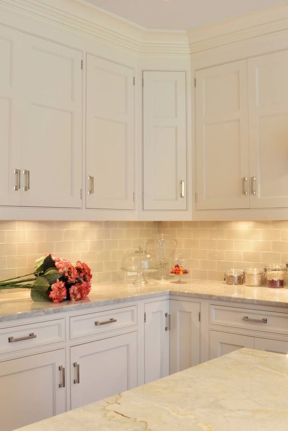 a sleek, neutral kitchen with cream cabinets, a gray subway tile backsplash, and gray countertops