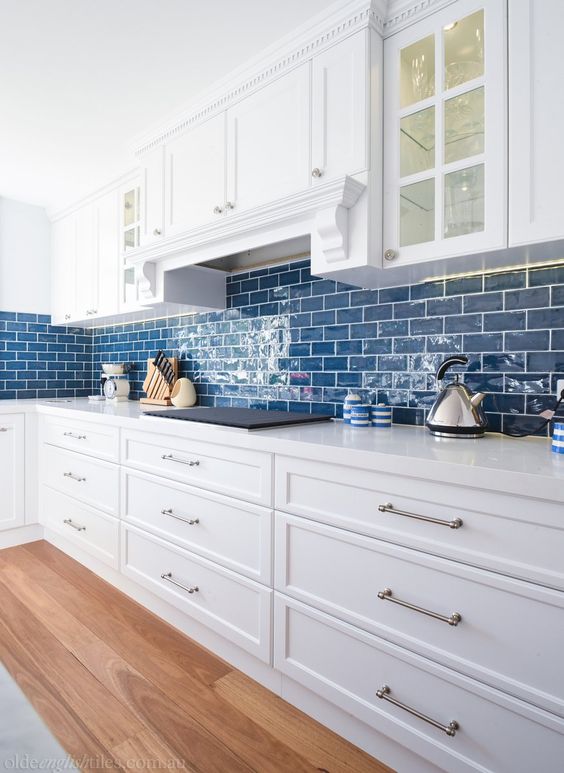 A cozy coastal kitchen in white with bold blue subway tiles that add color and indicate the location