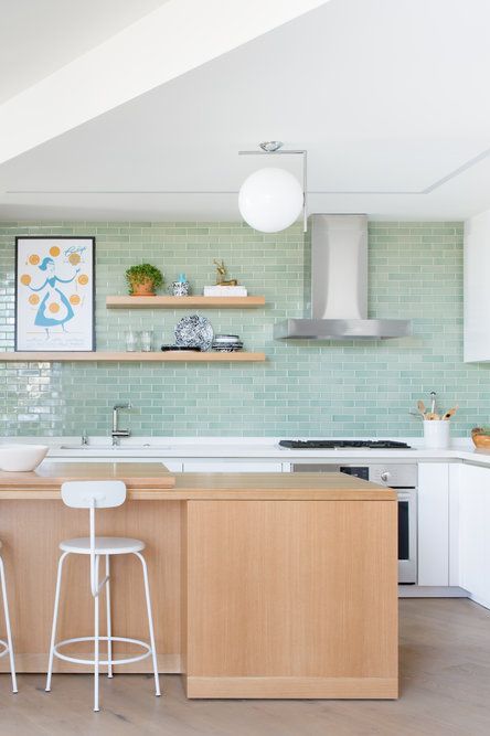 A pretty white kitchen with turquoise subway tiles, a wooden island and shelves, and white furniture is very cool