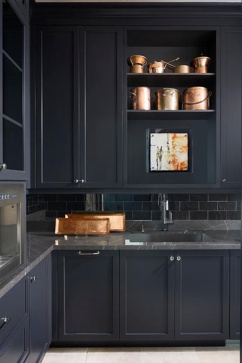 A sophisticated, moody black kitchen with gray marble countertops and a black subway tile backsplash is totally chic