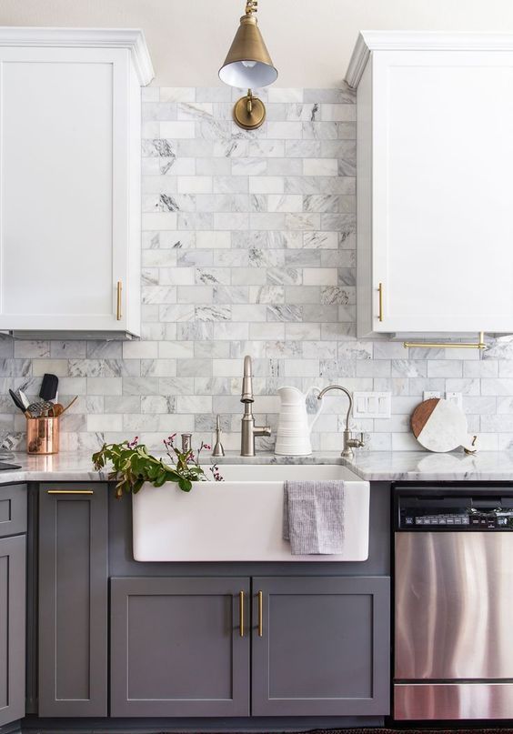 A two-tone white and gray farmhouse kitchen with a marble tile backsplash and mixed metal accents