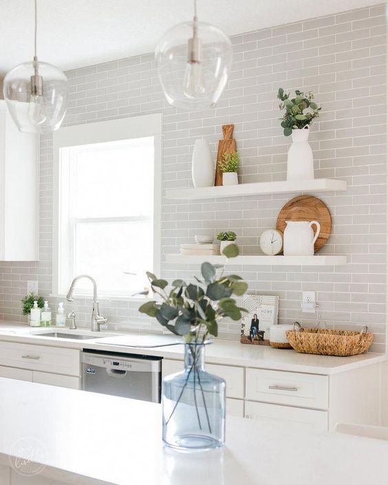 A white kitchen with dove gray subway tiles and green accents feels fresh and ethereal