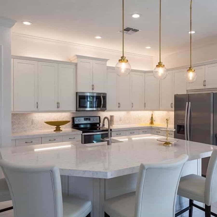 Large white cabinet kitchen with curved island and hanging ceiling lights 