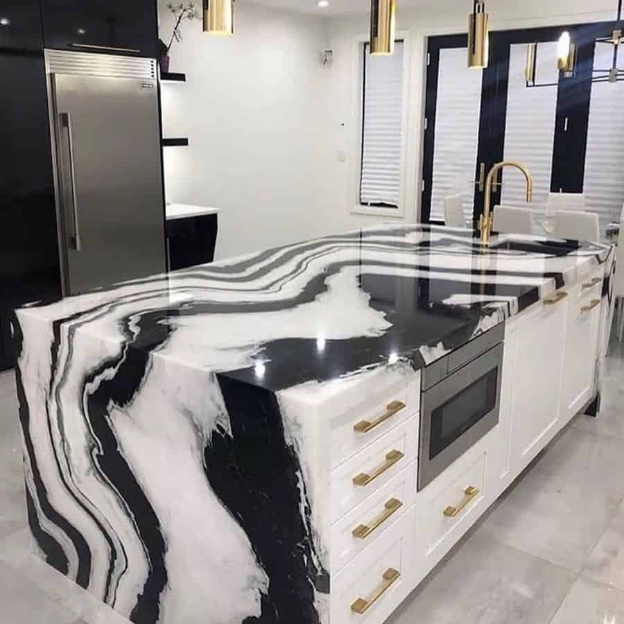 Kitchen island with black and white marble countertop and gold accents 