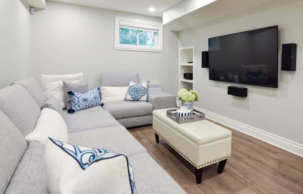 small white living room with gray sofa and wall-mounted TV