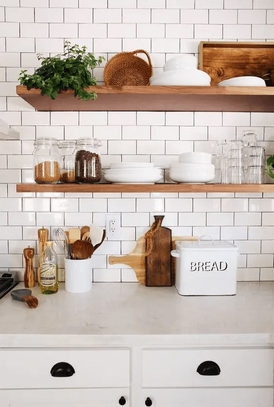 A cozy farmhouse kitchen features white subway tiles with black grout and natural wood shelves