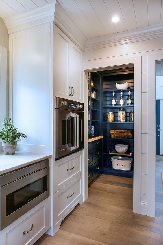 a small pantry with navy blue cabinets and open shelves, with built-in lights and plenty of storage space
