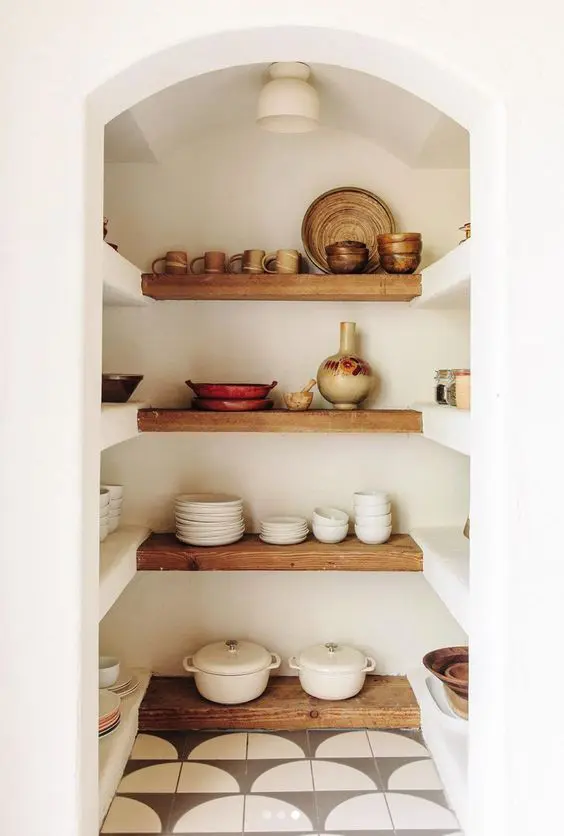 a beautiful Mediterranean walk-in pantry with arched entry, built-in and stained shelves and plenty of dishes and cookware