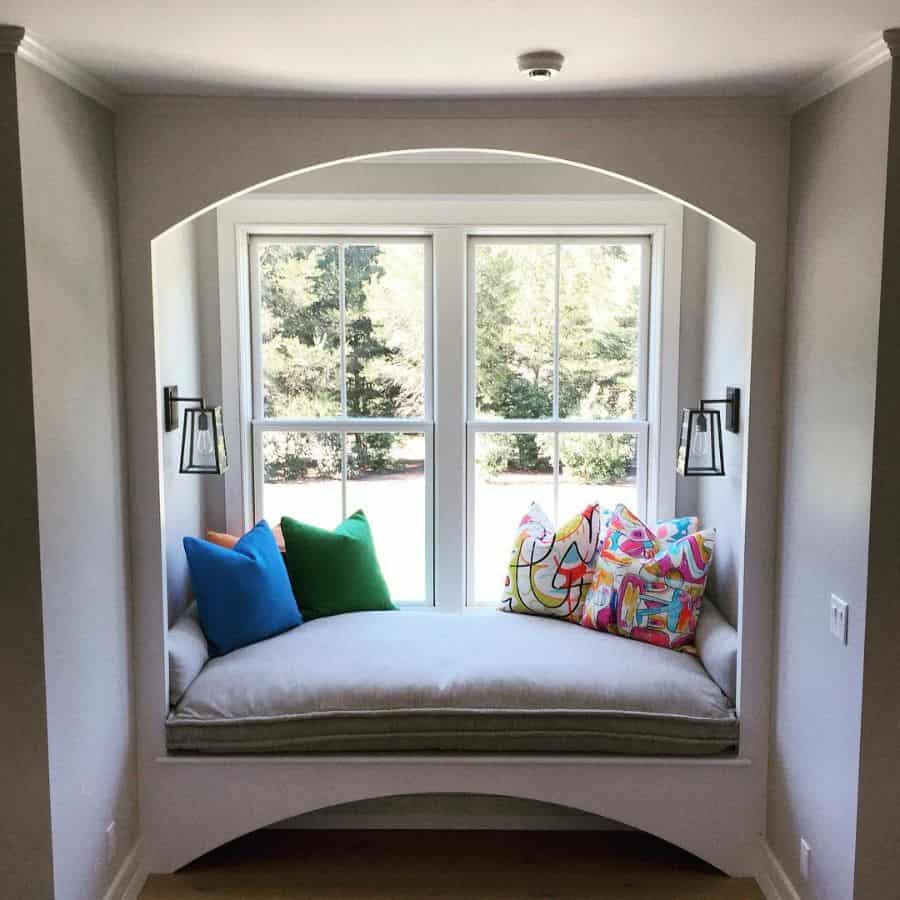 small window seat, colorful pillows, sconces, lights 