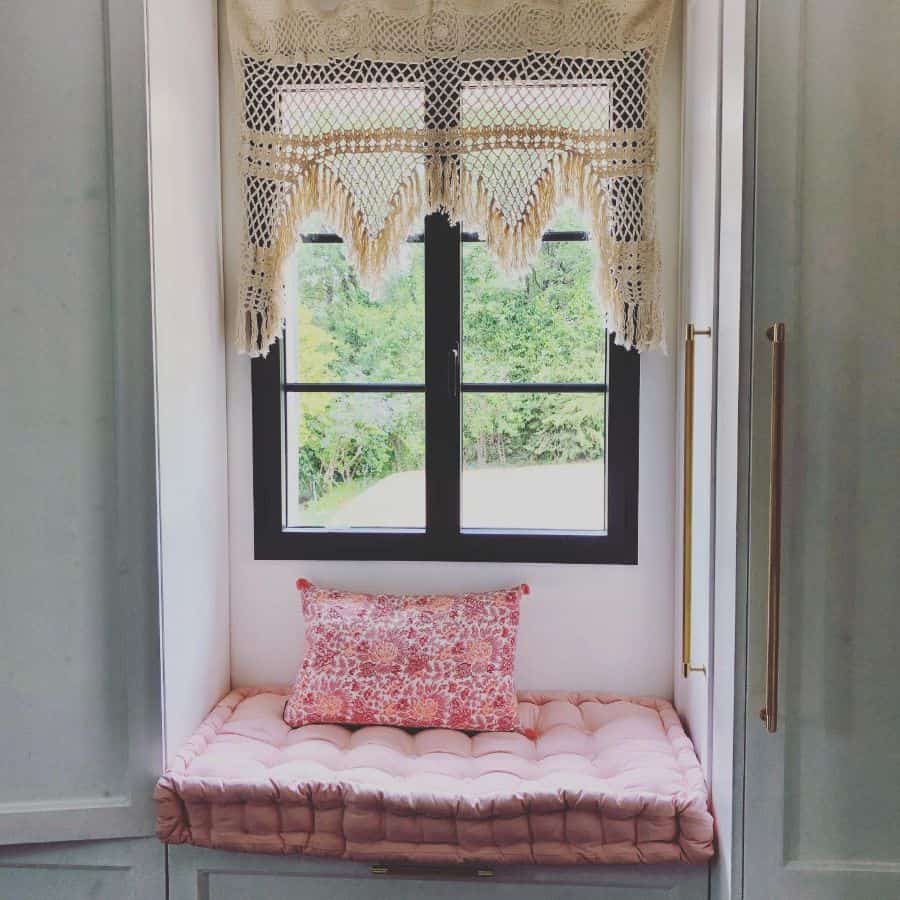 small window seat, pink cushions, black window frame 