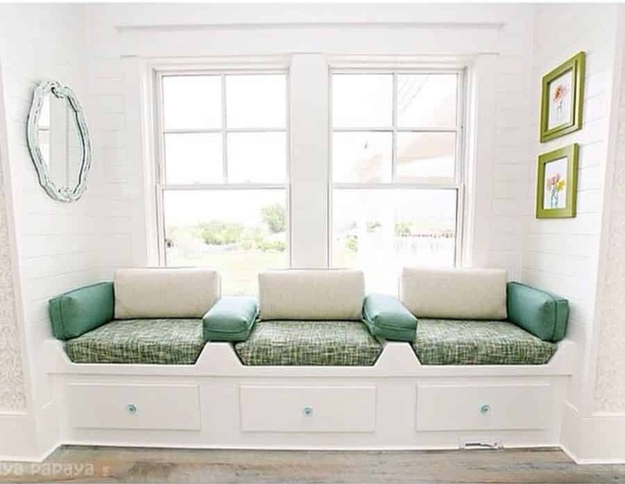 Country style window seat with green cushions underneath 
