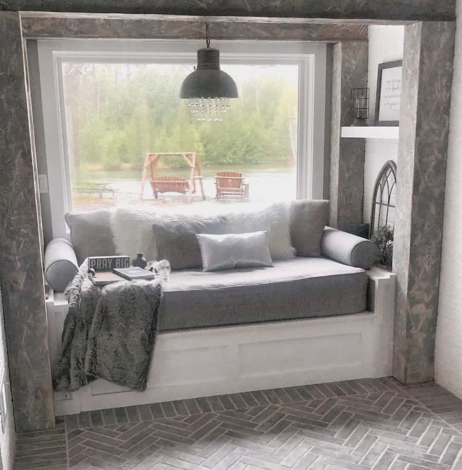 Comfortable window seat with gray cushions and pillows 