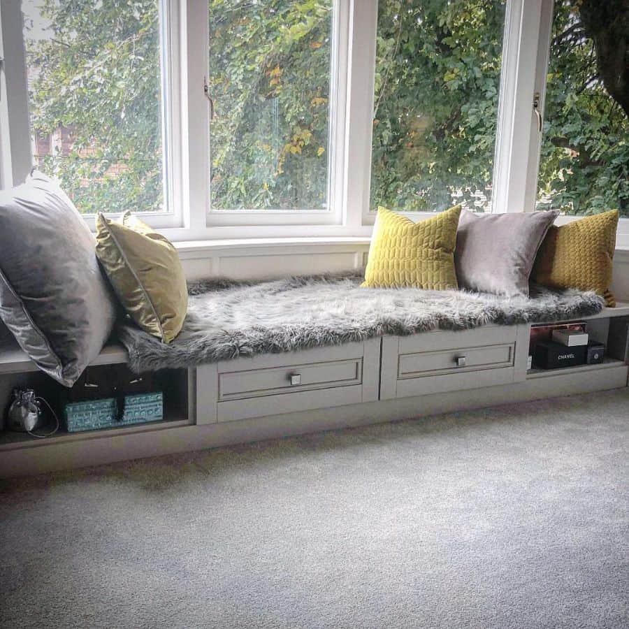 Window seat with gray carpet under storage 