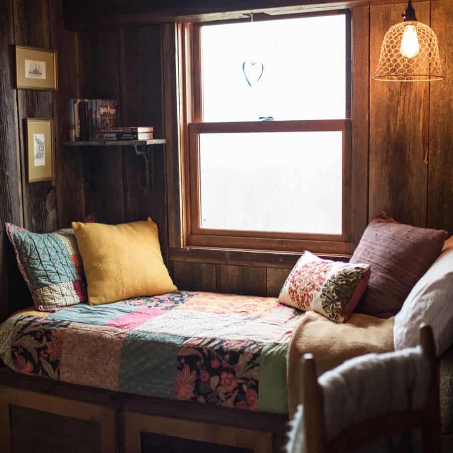 Window seat made of wooden panels with colorful cushions and carpet 