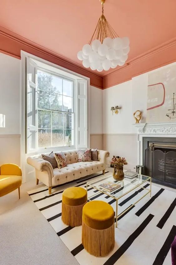 a bold living room with an orange ceiling, white walls and floors, a chic Chesterfield sofa, yellow furniture and a fireplace