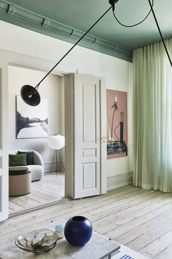 a chic Scandinavian home with neutral walls, a bold green ceiling, lime green curtains, a coffee table and a navy blue vase
