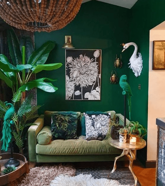 a bold living room with emerald green walls, a muted green sofa, potted plants and an emerald green parrot figurine