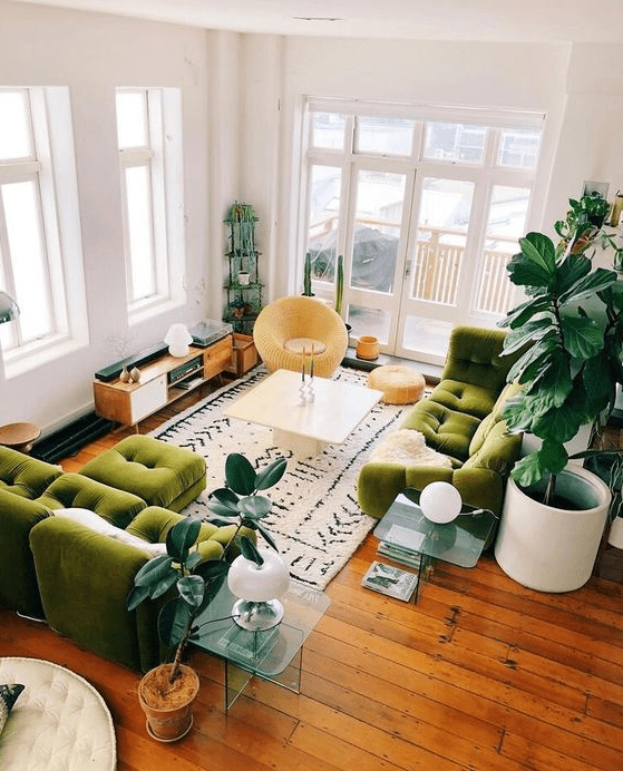 a modern boho-style living room with green sofas and a stool, a coffee table, side tables, a TV and a round chair