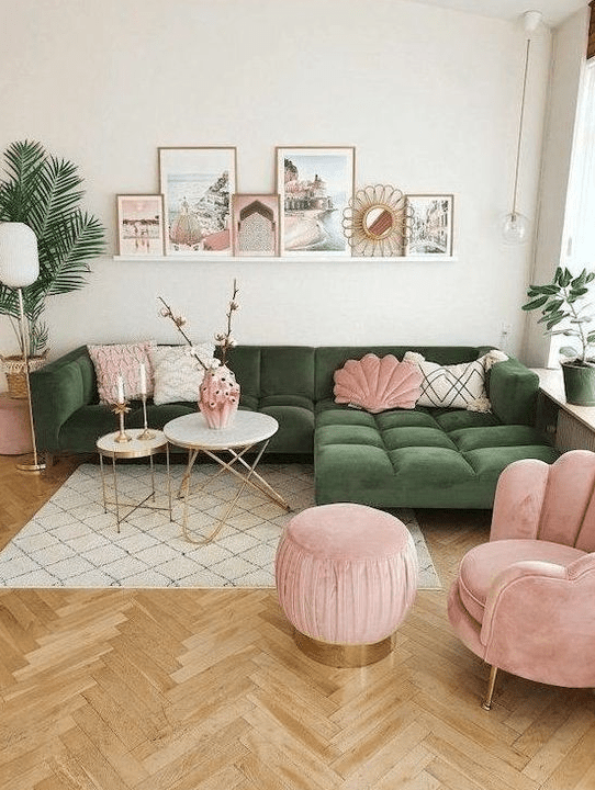 a beautiful living room with a green seating area, a pink chair and stool, some pillows, a gallery wall and potted plants
