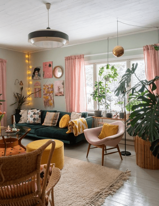 a bright living room with light green walls, a dark green sofa and pillows, a pink gallery wall, a chair and curtains and some yellow accents