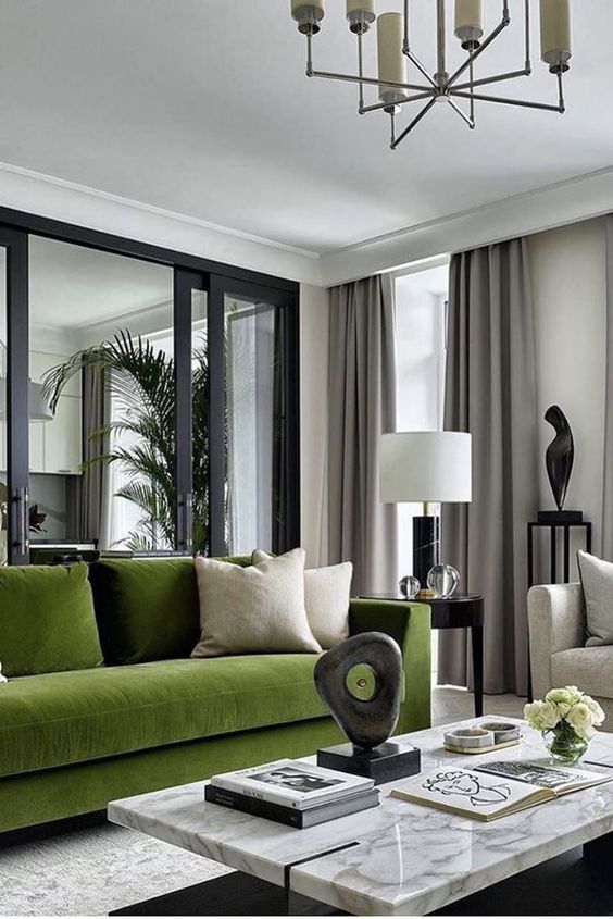 a luxury modern living room with a green sofa and cushions, a marble coffee table, a side table with a lamp and gray curtains