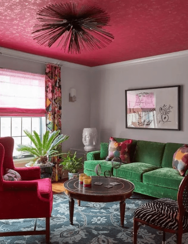 a catchy eclectic living room with a green sofa, a pink chair, a curtain and blanket, a round table and a zebra print chair