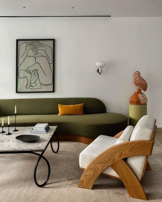 a sophisticated, modern living room with a green curved sofa, a cream chair, a coffee table and some sophisticated decor
