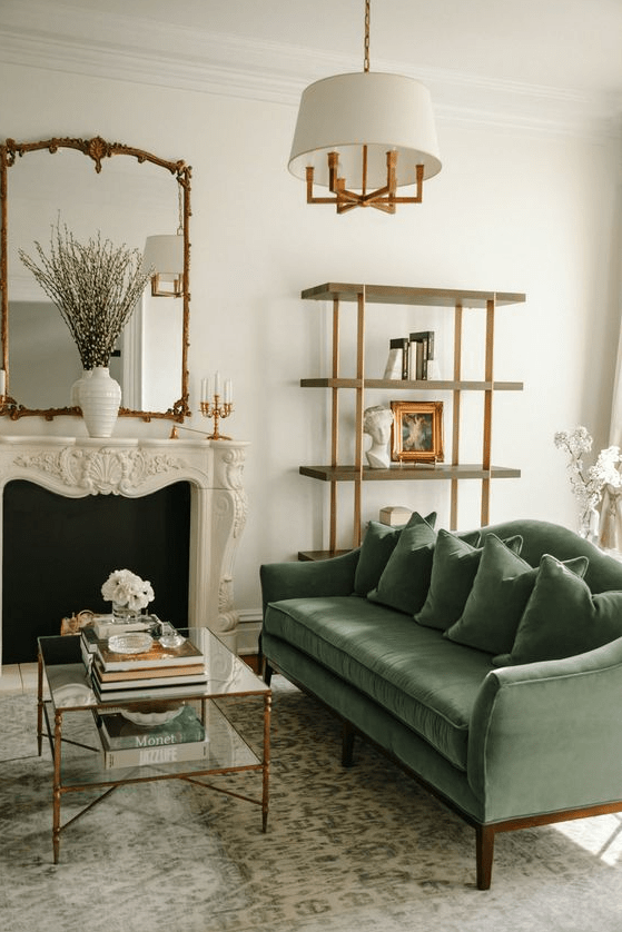 an elegant living room with a fireplace, a green sofa, a tiered coffee table, a shelf, a chandelier and a mirror