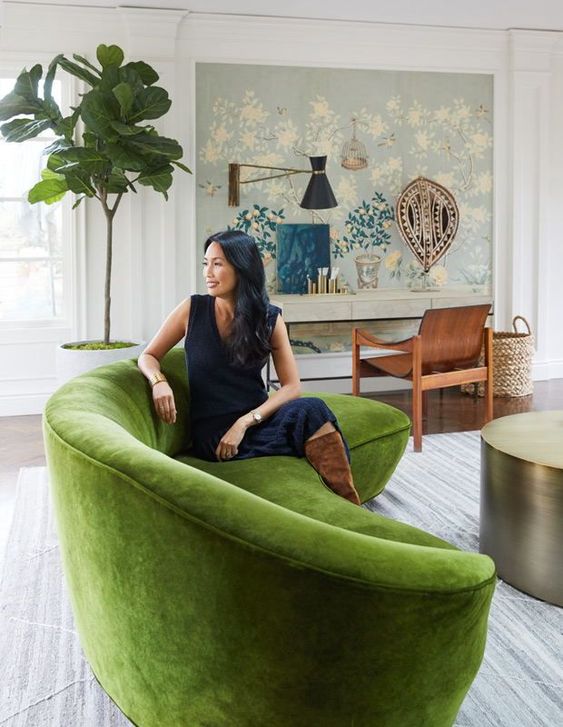 an exquisite living room with a green curved sofa, a metal coffee table, a console with a curved chair and a potted tree