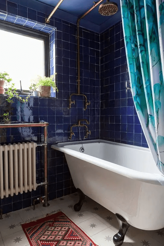 an eye-catching bathroom with vibrant bright blue zellige tiles, a star-patterned tile floor, a clawfoot tub and a bold printed curtain