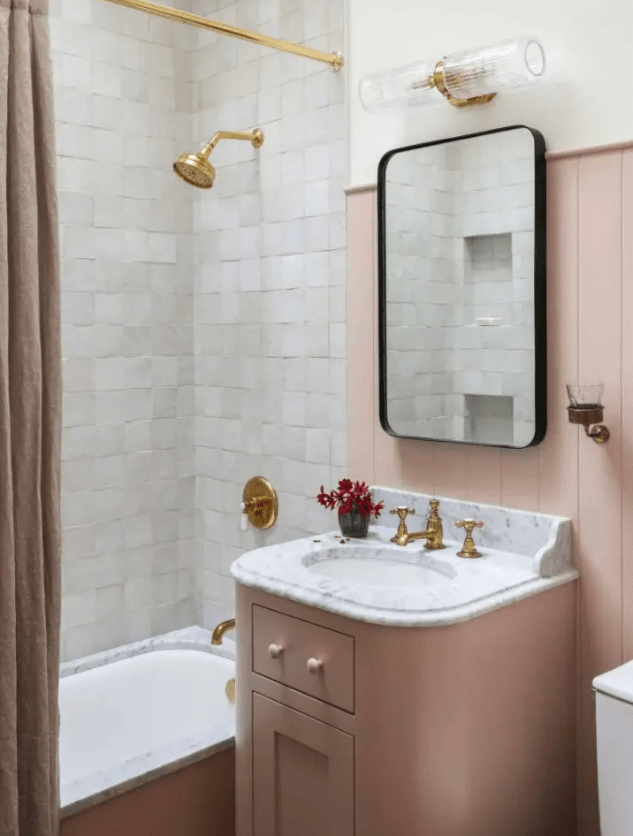 a beautiful, modern bathroom with a vanity, wall and curtain in dusty pink, white zellige tiles and gold fittings