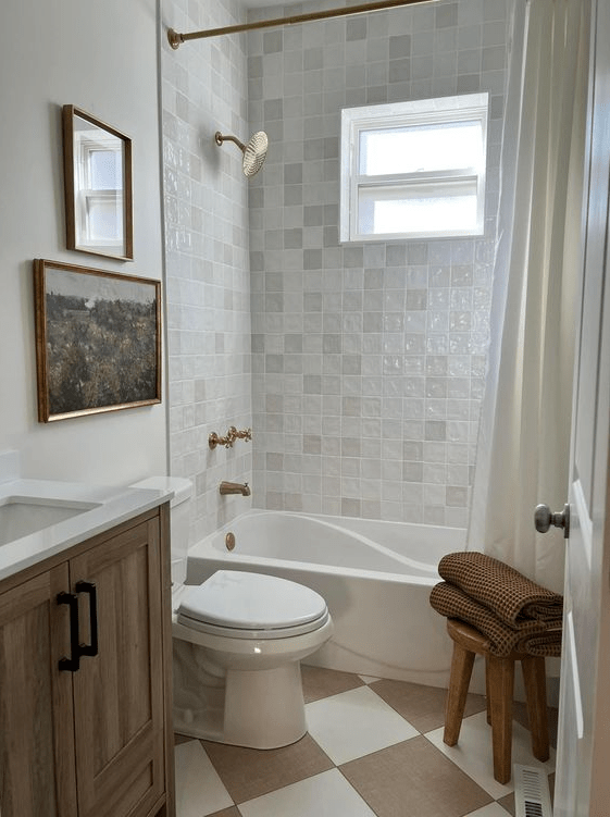 a neutral guest bathroom with zellige tiles, beige and white checkered floors, stained furniture and a gallery wall