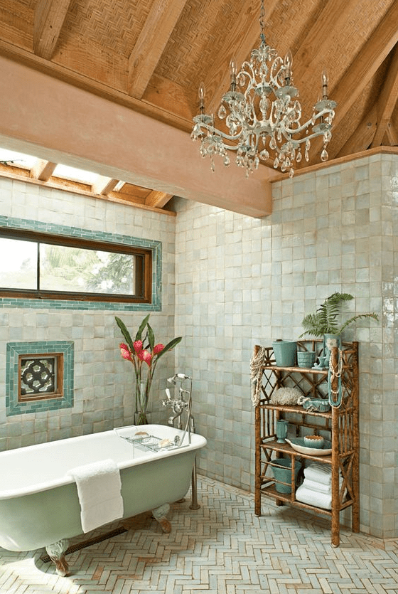 a whimsical bathroom with zellige square and herringbone tiles, a mint tub, a skylight and window, and a chic chandelier