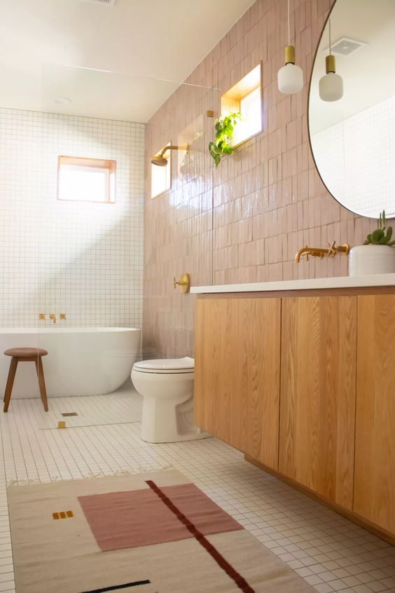 an inviting bathroom with white square and pink zellige tiles, a stained vanity, a shower area and a bathtub, a round mirror and a hanging lamp