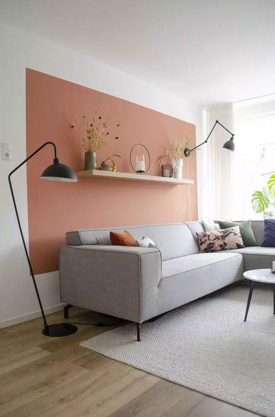 a Scandinavian living room with a terracotta accent wall, a gray corner sofa, black lamps and a coffee table
