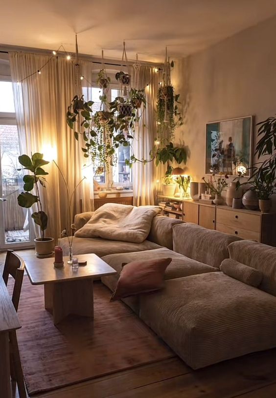 a calming, earthy living room with a low greige sofa, a burgundy rug and pillows, a coffee table and lots of plants